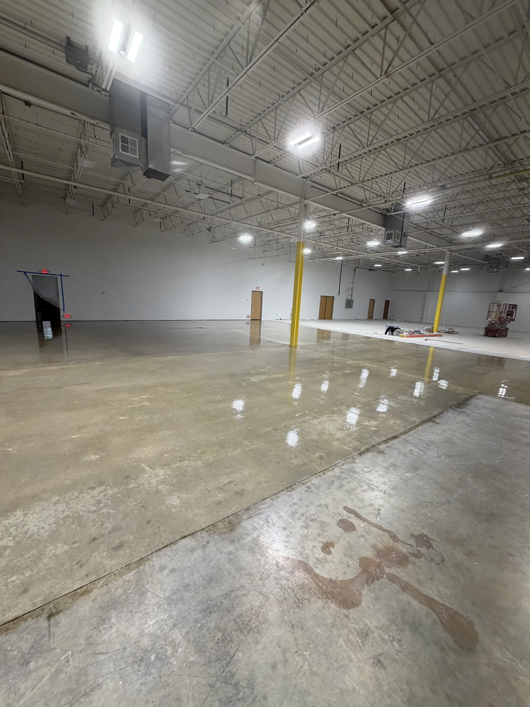 Triumph Concrete Coating Commercial concrete floor during sealer application with finished and unfinished zones visible
